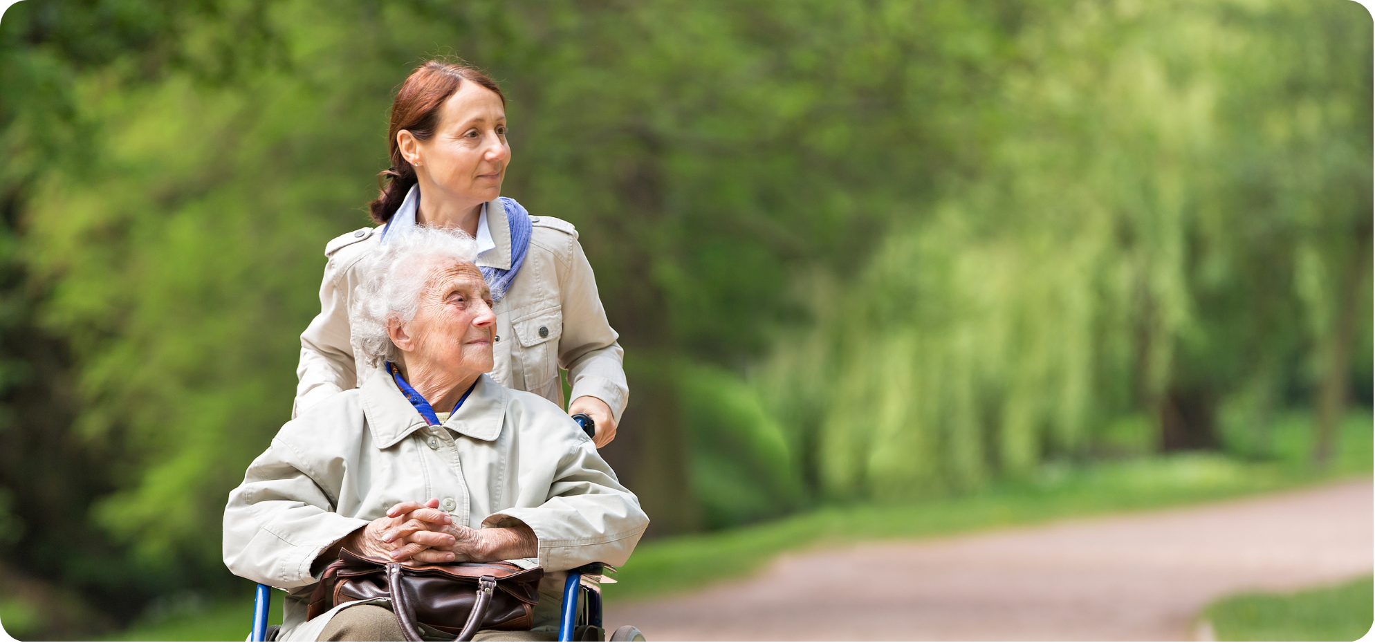 A caregiver walking with a resident in a park
